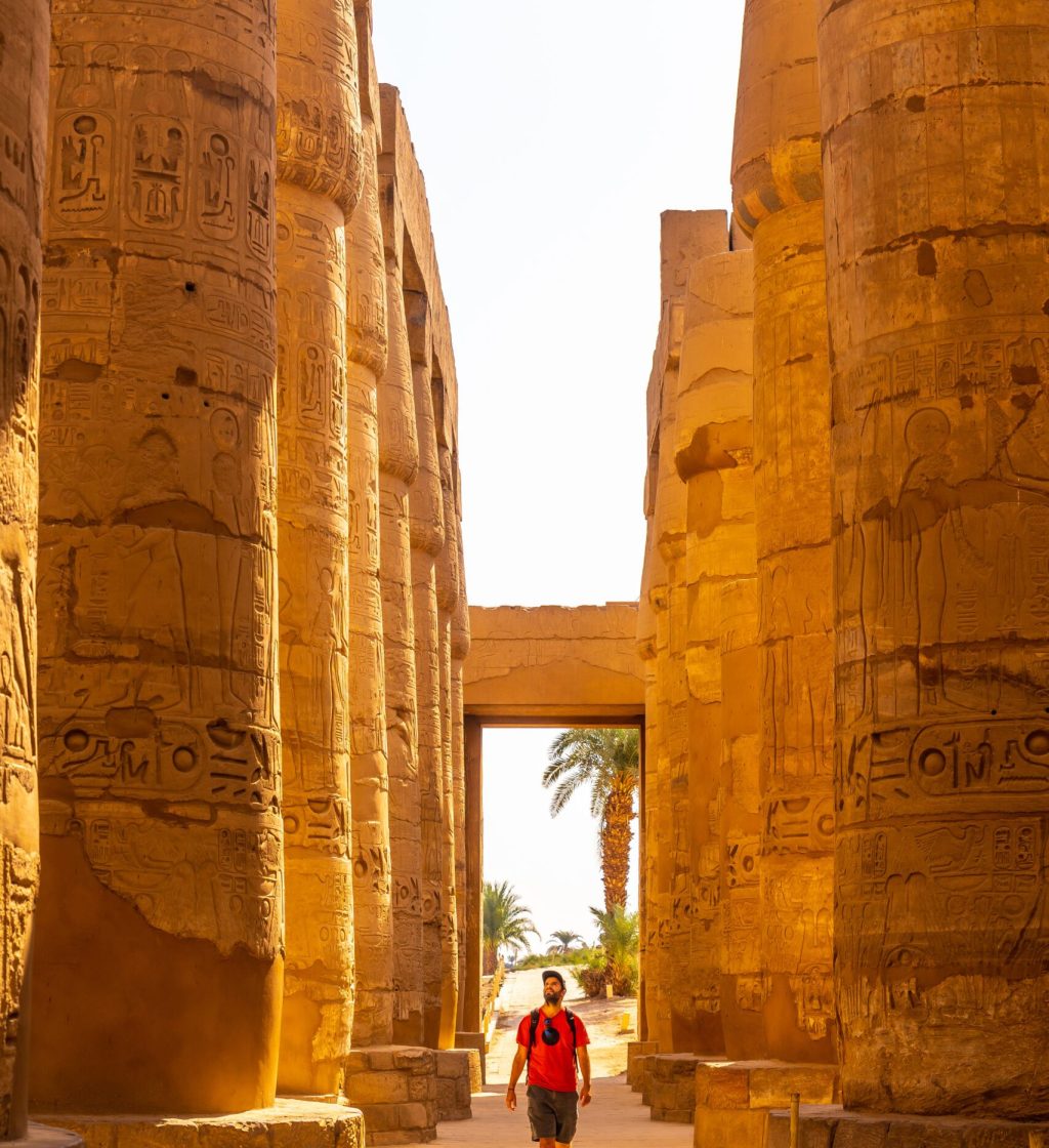 A young man strolling between the hieroglyphic columns of the Temple of Karnak, the great sanctuary of Amun. Egypt