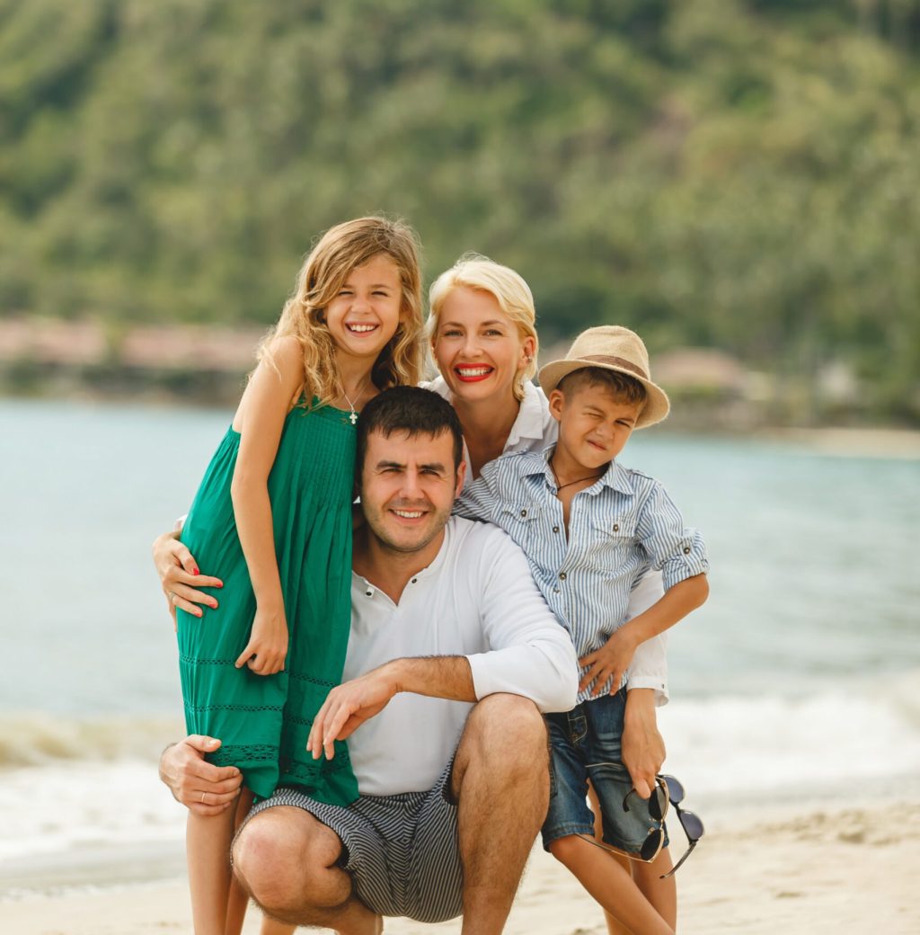 beautiful happy family on vacation embracing on beach and looking at camera