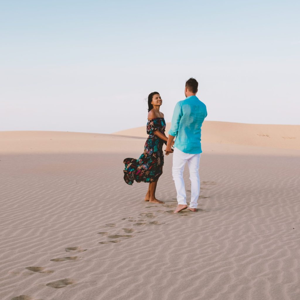 couple walking at the beach of Maspalomas Gran Canaria Spain, men and woman at the sand dunes desert of Maspalomas Gran Canaria