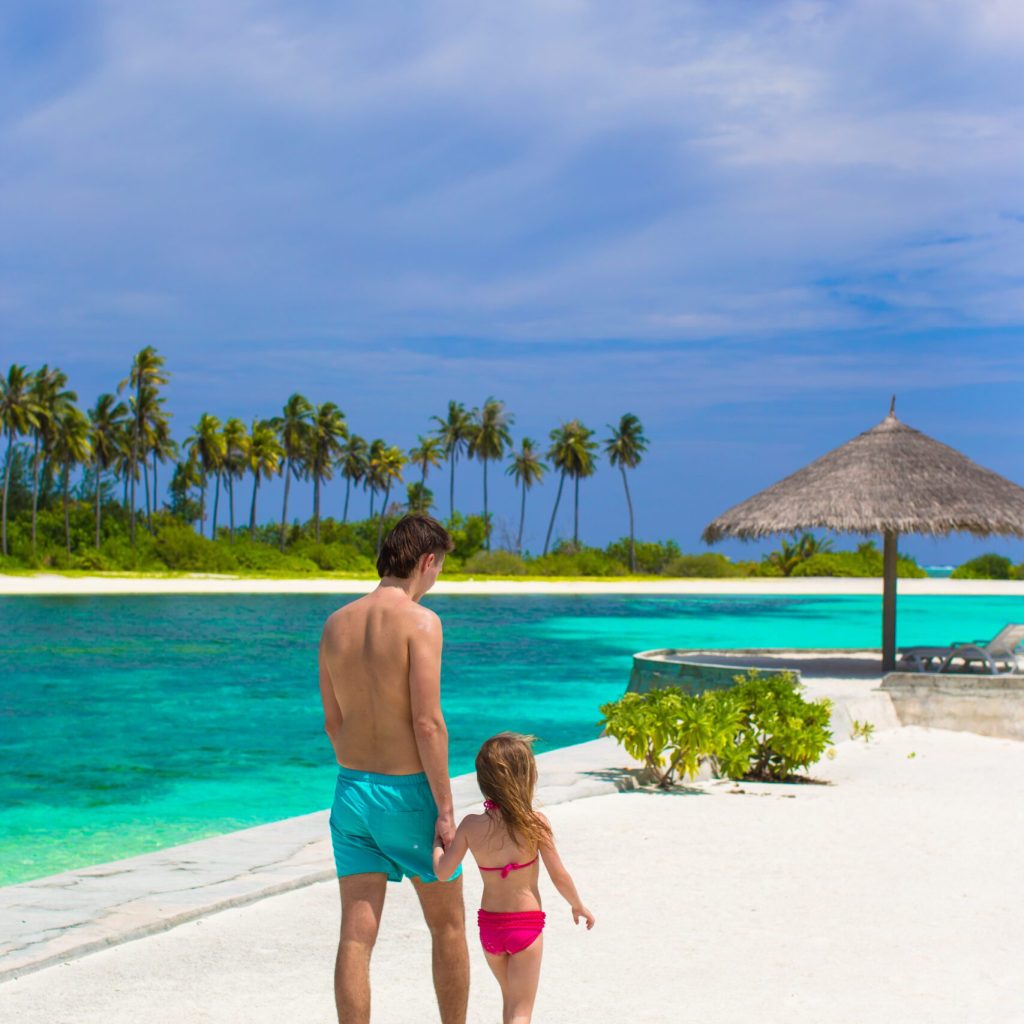 Happy father and his adorable little daughter at white sandy beach