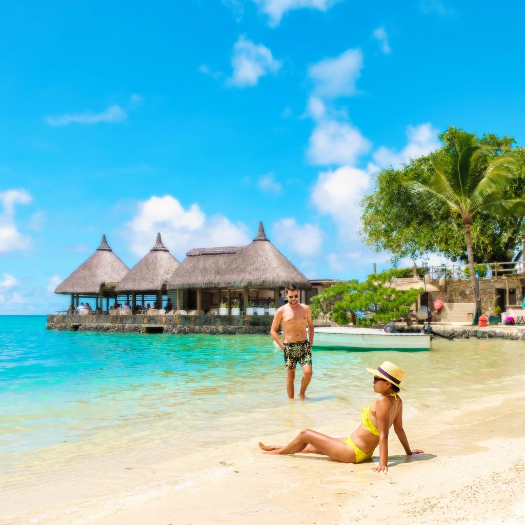 Man and Woman on a tropical beach in Mauritius, a couple on a honeymoon vacation in Mauritius on a sunny day with turqouse colored ocean