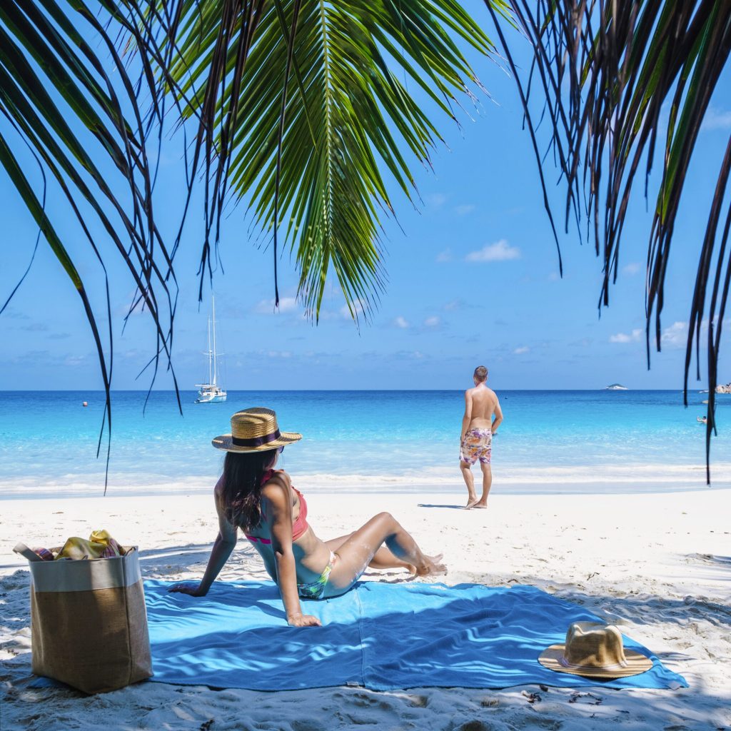 Praslin Seychelles tropical island with tropical beaches and palm trees, a couple of men and women mid age on vacation at Seychelles visiting the tropical beach of Anse Lazio Praslin Seychelles.