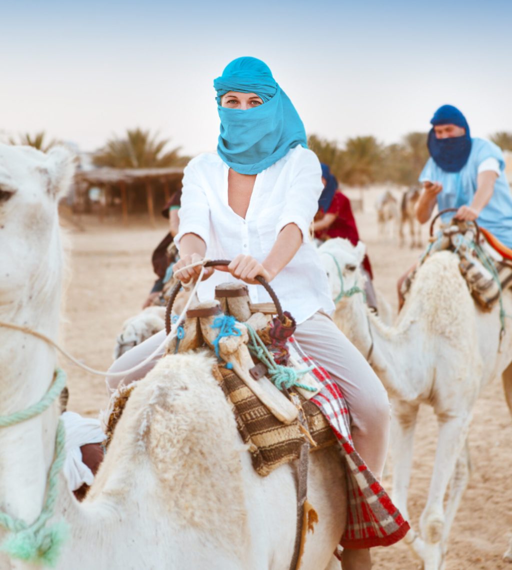 Young caucasian woman tourist riding on camel in Sahara desert. Tunis